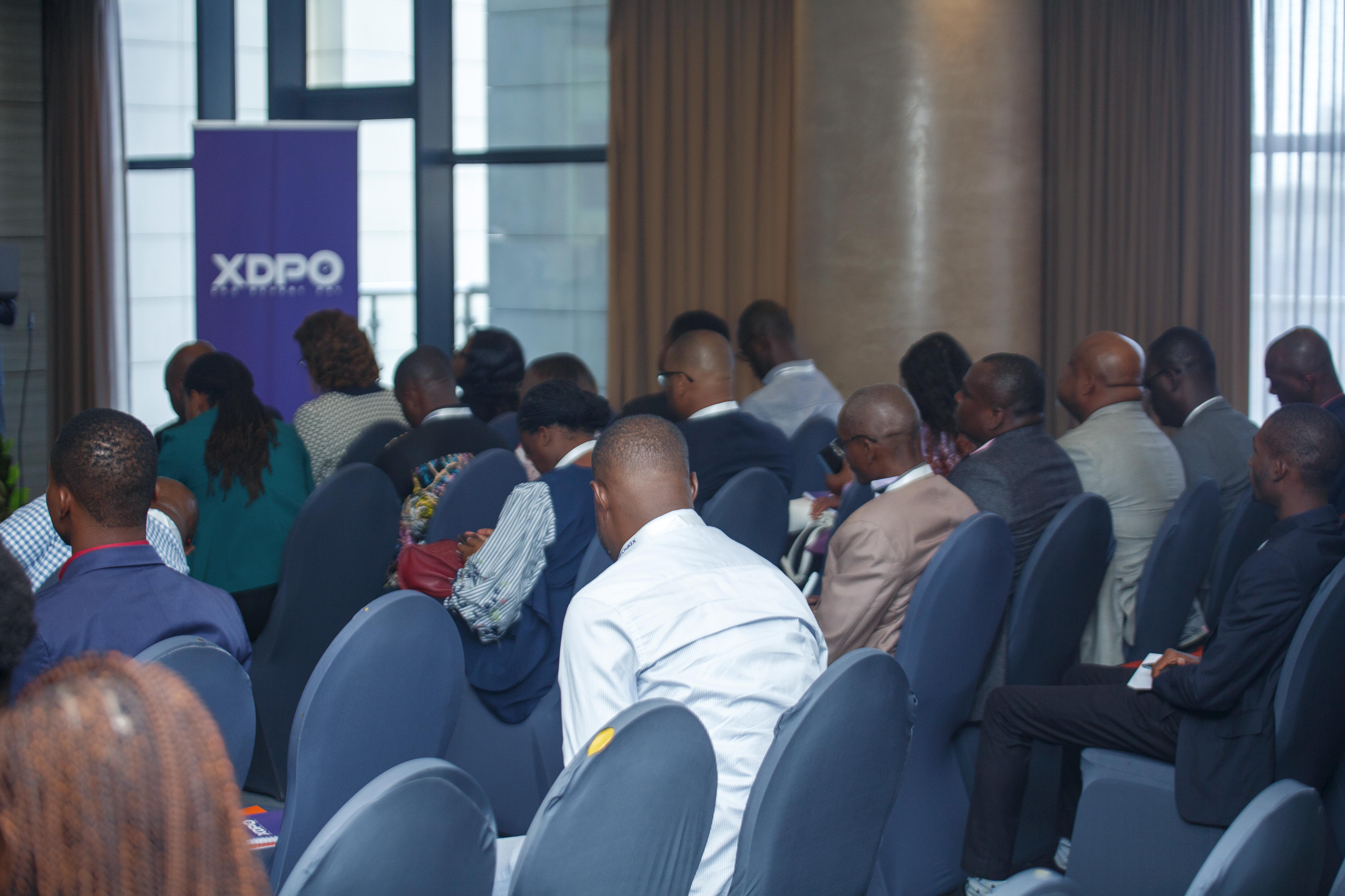Public assis lors d'une conférence XDPO, avec la bannière XDPO en arrière-plan